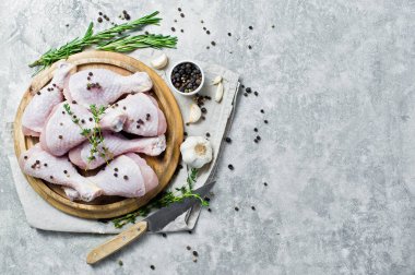 Çiğ tavuk budu. Yemek pişirmek için malzemeler: biberiye, kekik, sarımsak, biber. Gri arka plan, üstten görünüm, metin için yer.