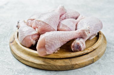 Çiğ tavuk budu. Gri arka, yan görünüm.