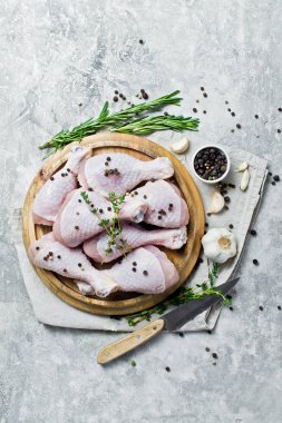 Tavuk bacağı çeyrek. Yemek pişirmek için malzemeler: biberiye, kekik, sarımsak, biber. Gri arka plan, üstten görünüm, metin için yer.