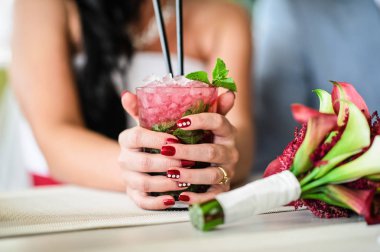 Gelin bir bardak Mojito, düğün buket t üzerinde tutuyor