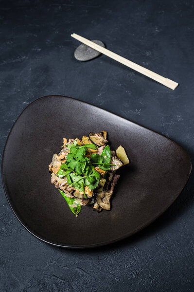 Salad with baked beef tenderloin and eggplant, dark background