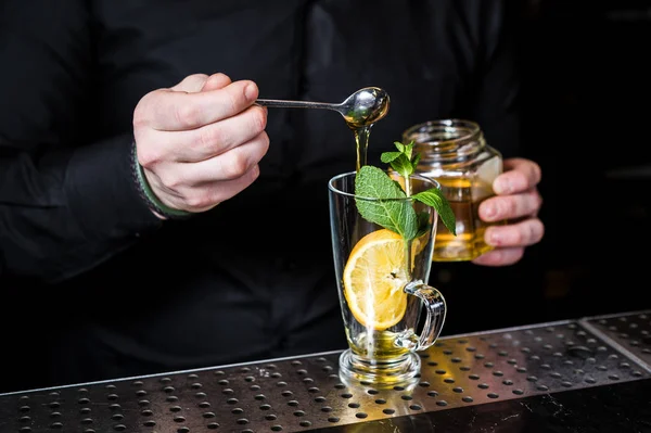 Μπάρμαν προετοιμάζει τσάι φρούτων με κράνμπερι σε ένα ποτήρι, σκούρο β — Φωτογραφία Αρχείου
