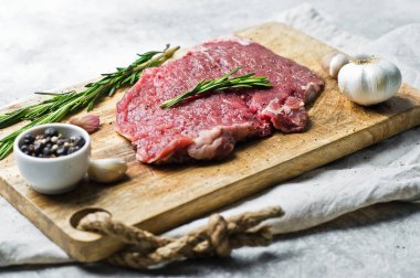 Ham sığır eti biftek rosemary ile Ahşap doğrama tahtası üzerinde yan. 