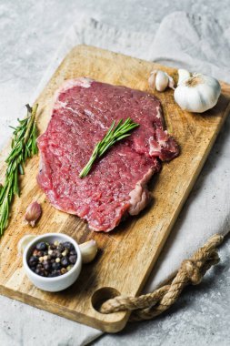 Ham sığır eti biftek rosemary ile Ahşap doğrama tahtası üzerinde yan. 