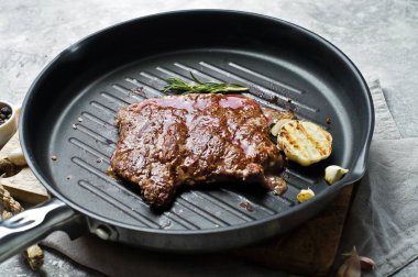 Barbekü biftek tavada sığır eti. Gri arka plan, üstten görünüm, uzay için 