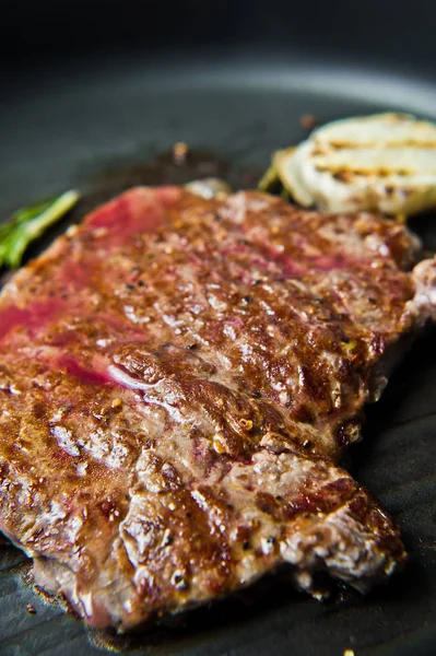 Beef flank steak in the pan. Dark background, side view, selecti