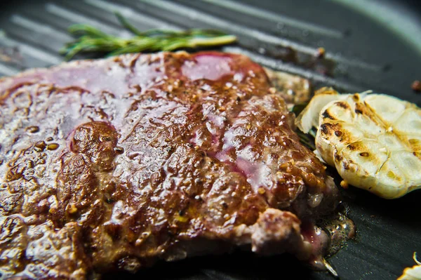 Beef flank steak in the pan. Dark background, side view, selecti