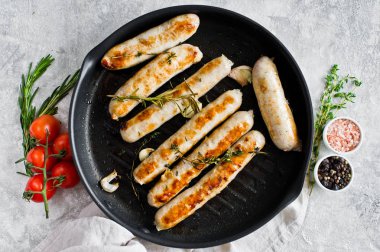 Kızartma tavasında kızarmış sosis. Gri arka plan, üst görünüm