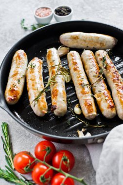 Kızartma tavasında kızarmış sosis. Gri arka plan, yan görünüm