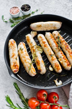 Kızartma tavasında kızarmış sosis. Gri arka plan, üst görünüm