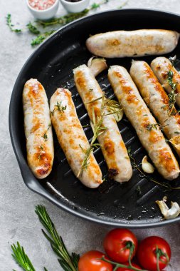 Kızartma tavasında kızarmış domuz eti ve tavuk sosisi. Gri arka plan