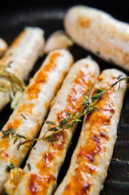 Kızartma tavasında kızarmış domuz eti ve tavuk sosisi. Gri arka plan