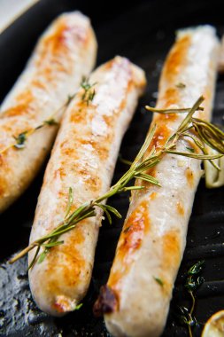 Kızartma tavasında kızarmış domuz eti ve tavuk sosisi. Gri arka plan