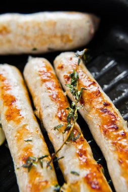 Bir tavada biftek ve domuz sosisi. Gri arka plan, s