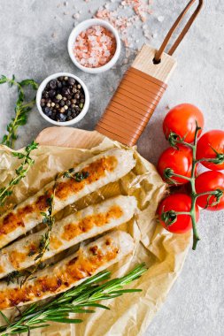 Ahşap bir tahta doğrama üzerinde kızarmış domuz sosis. Gri arka plan,