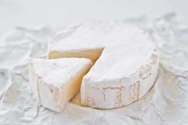 Beyaz kağıda camembert peyniri. Beyaz arka plan, yan görünüm, CL