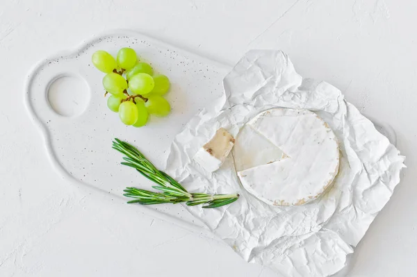 Camembert fromage aux noix sur une planche à découper blanche, raisins, ros — Photo