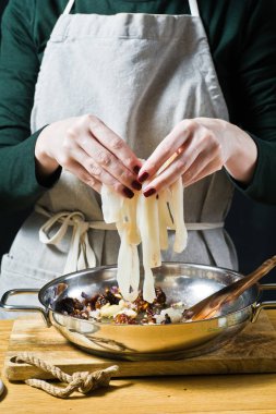 Şef, tavada kalamar koyar. Siyah arka plan, yan görünüm, mutfak