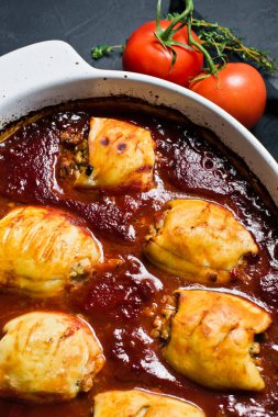 Domates soslu fırında kalamar ile çanağı. Siyah arka plan, top vie