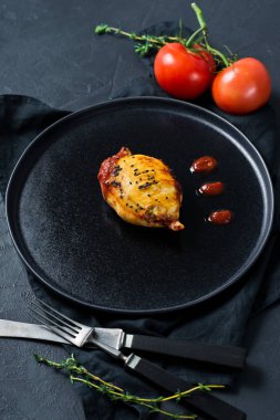 Siyah bir tabakta domates soslu fırında kalamar. Siyah arka plan, 