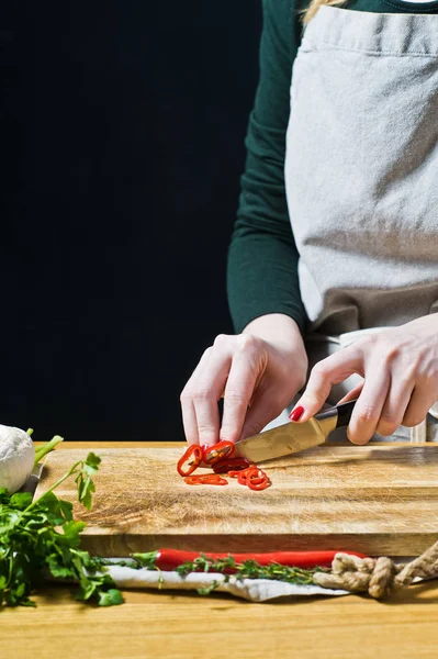 Händerna på kocken skär Chile peppar. Svart bakgrund, s — Stockfoto