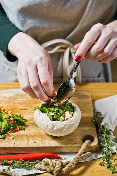 Kocken förbereder fyllda champinjoner. Svart bakgrund, sidovy — Stockfoto