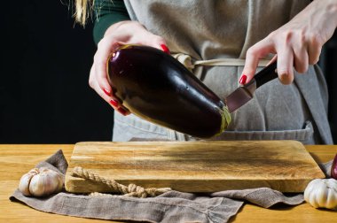 Şef patlıcan bir ahşap kesme tahtası dilimleme. Yan