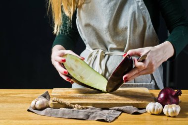 Şef patlıcan bir ahşap kesme tahtası dilimleme. Yan