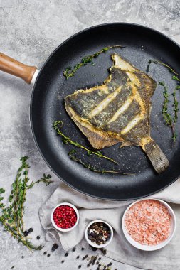 Bir tavada kızarmış pisi. Gri arka plan, üstten görünüm.