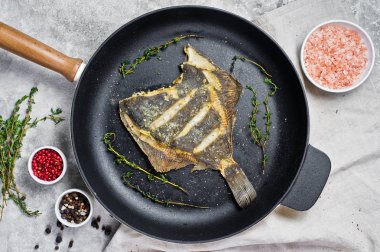 Bir tavada kızarmış pisi balığı. Gri arka plan, üstten görünüm.