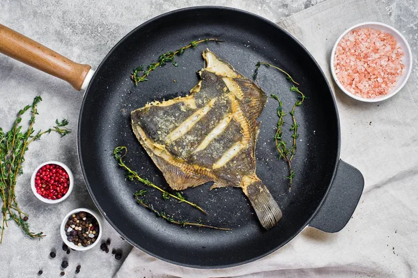 Bir tavada kızarmış pisi balığı. Gri arka plan, üstten görünüm.