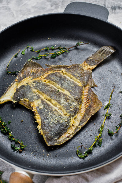 Fried flounder in a pan. Gray background, top view.