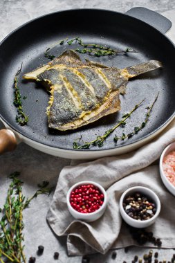 Bir tavada kızarmış pisi. Gri arka plan, üstten görünüm.