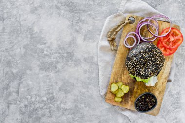 Ahşap bir tahta doğrama üzerinde Juicy çift siyah Burger. Üstteki görünüm, gri arka plan, metin alanı.