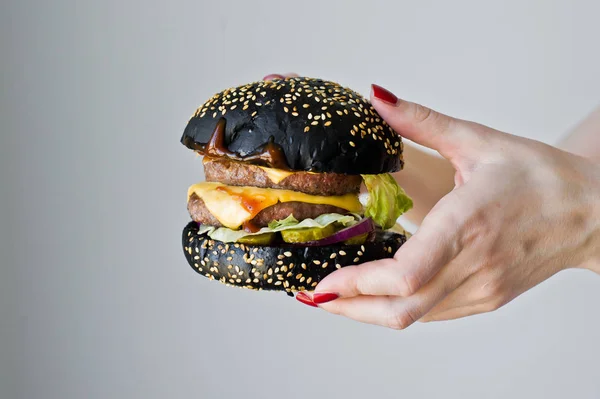 Hands holding a juicy Burger. Side view, gray background, space for text.