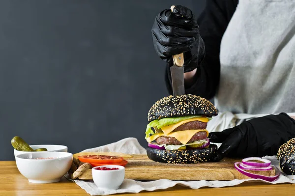 El chef cocinando una hamburguesa jugosa. El concepto de cocinar hamburguesa con queso negro. Receta casera de la hamburguesa. Cocina, vista lateral, espacio para texto . — Foto de Stock