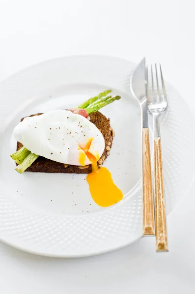 Toast avec œuf poché et asperges cuites au four. Fond blanc, vue latérale . — Photo