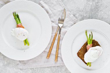 Pastırmalı kavrulmuş kuşkonmamış iki kızarmış yumurta. Gri arka plan, üst görünüm.