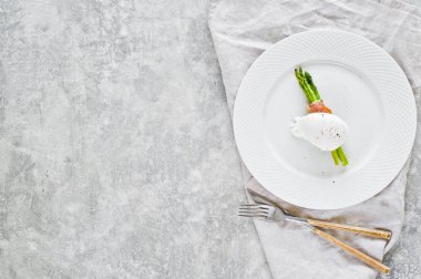 Domuz pastırması sarılmış kavrulmuş kuşkonmamış yumurta kızartılmış. Gri arka plan, üst görünüm, metin alanı.