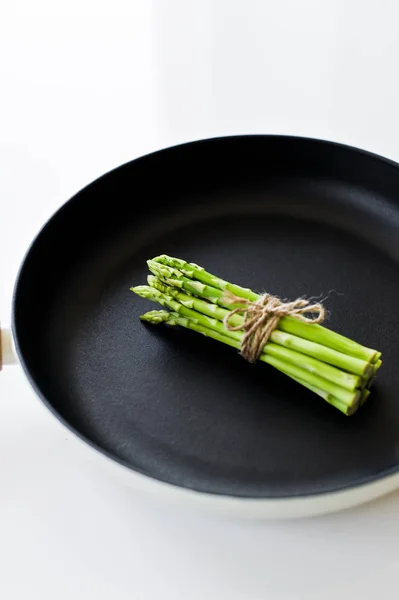 Mini asperges dans une casserole. Fond blanc, vue du dessus, espace pour le texte . — Photo