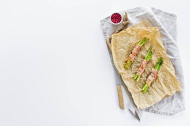 Pastırma içinde mini kuşkonmadan. Beyaz arka plan, üstteki görünüm, metin alanı.