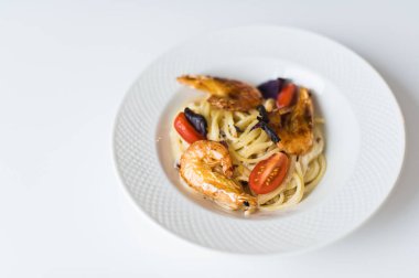 Beyaz plakalı karides makarna. Üstteki görünüm, beyaz arka plan.