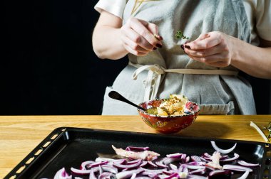 Aşçı kuzu bacağı için marinat hazırlar. Biberiye, keklik, karabiber. Siyah arka plan, yan görünüm, metin alanı