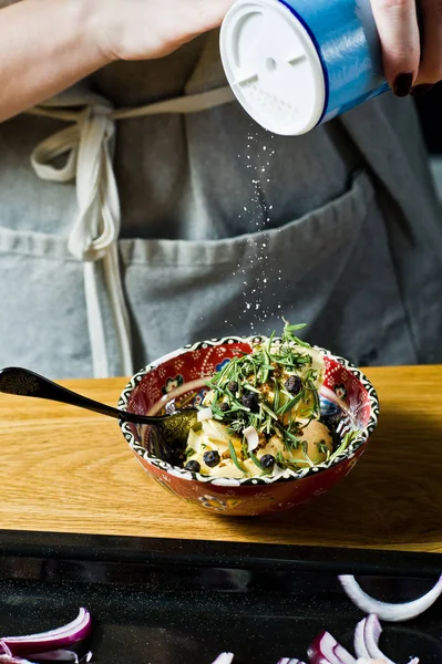 Aşçı kuzu bacağı için marinat hazırlar. Biberiye, keklik, karabiber. Siyah arka plan, yan görünüm, metin alanı