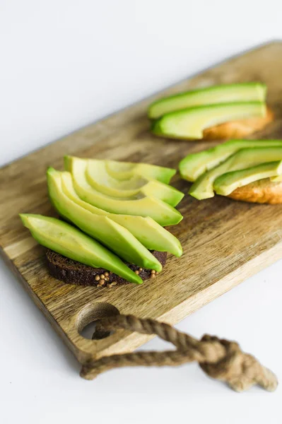 Sliced avocado on wood cutting Board.