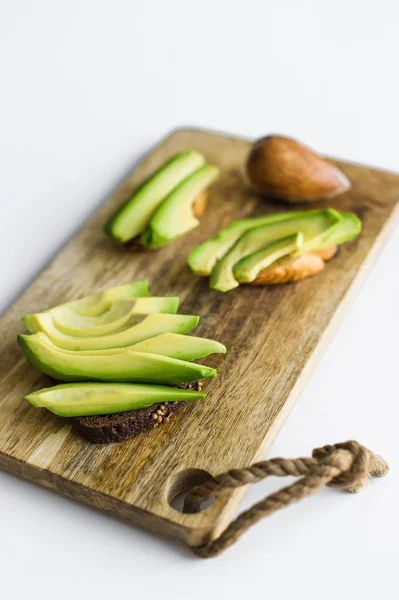 Sliced avocado on wood cutting Board.