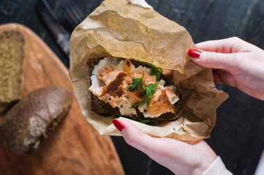 Yumuşak peynir ile siyah ekmek üzerinde füme somon ile Iskandinav sandviç tutan şefin elleri