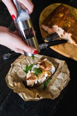 Yumuşak peynir ile siyah ekmek üzerinde füme somon fileto ile Şef biber maydanoz sandviç