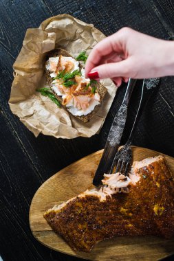 Şef, siyah ekmek ve yumuşak peynir üzerinde füme somon fileto ile bir sandviç üzerinde maydanoz Sprinkles