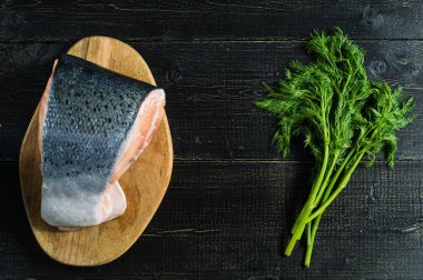 Siyah ahşap arka planda Atlantik çiğ somon, biftek ve maydanoz delikanlı